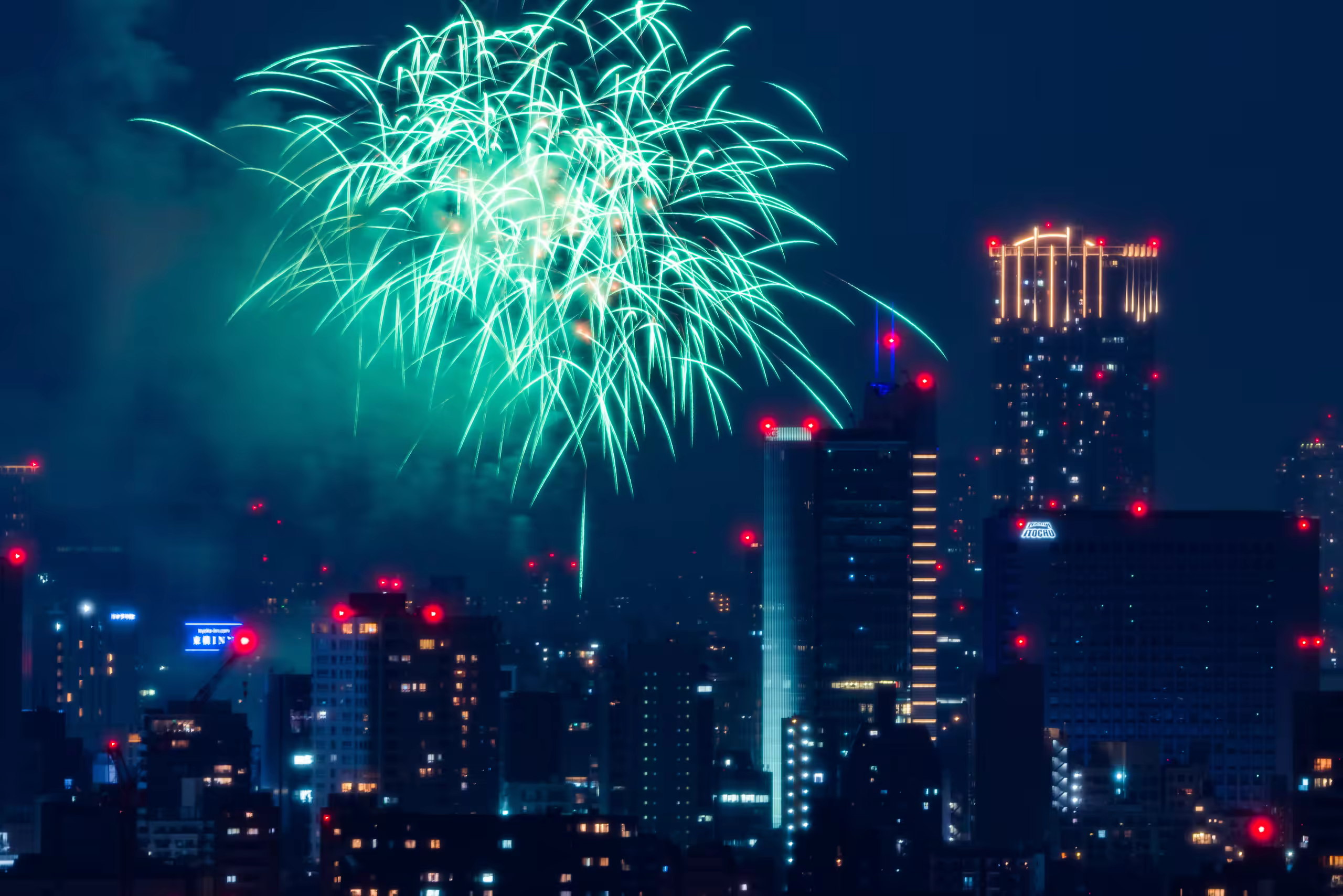 夜空に打ち上がる花火と都市のビル群